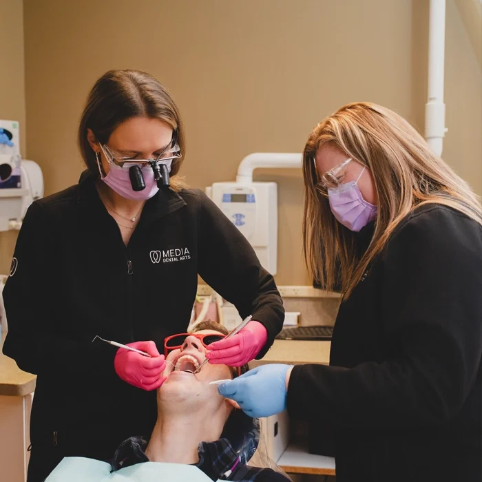 Dr. Alice Bassani performing an exam on a patient's teeth assisted by clinic staff